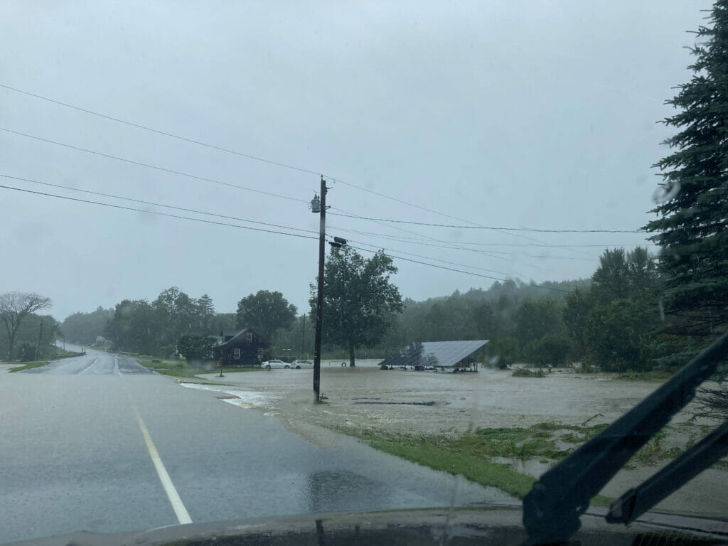 Rain water floods a yard and is encroaching on a road