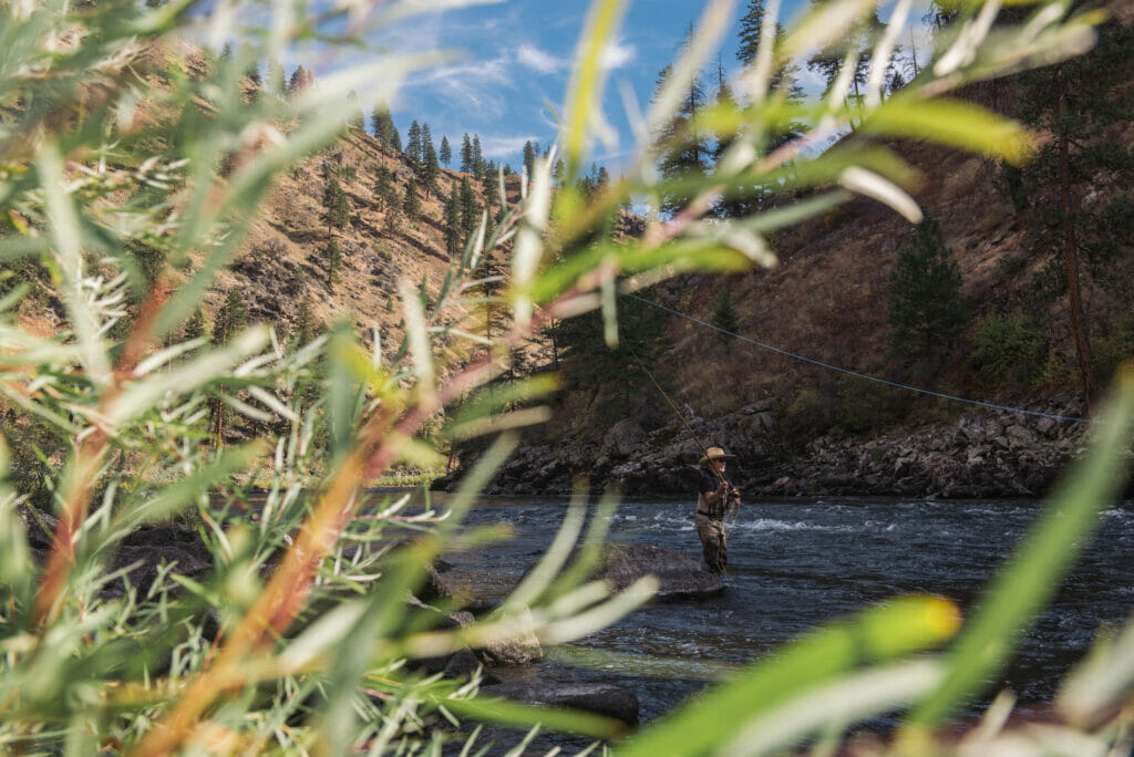 Man wish a hat fly fishing in a river