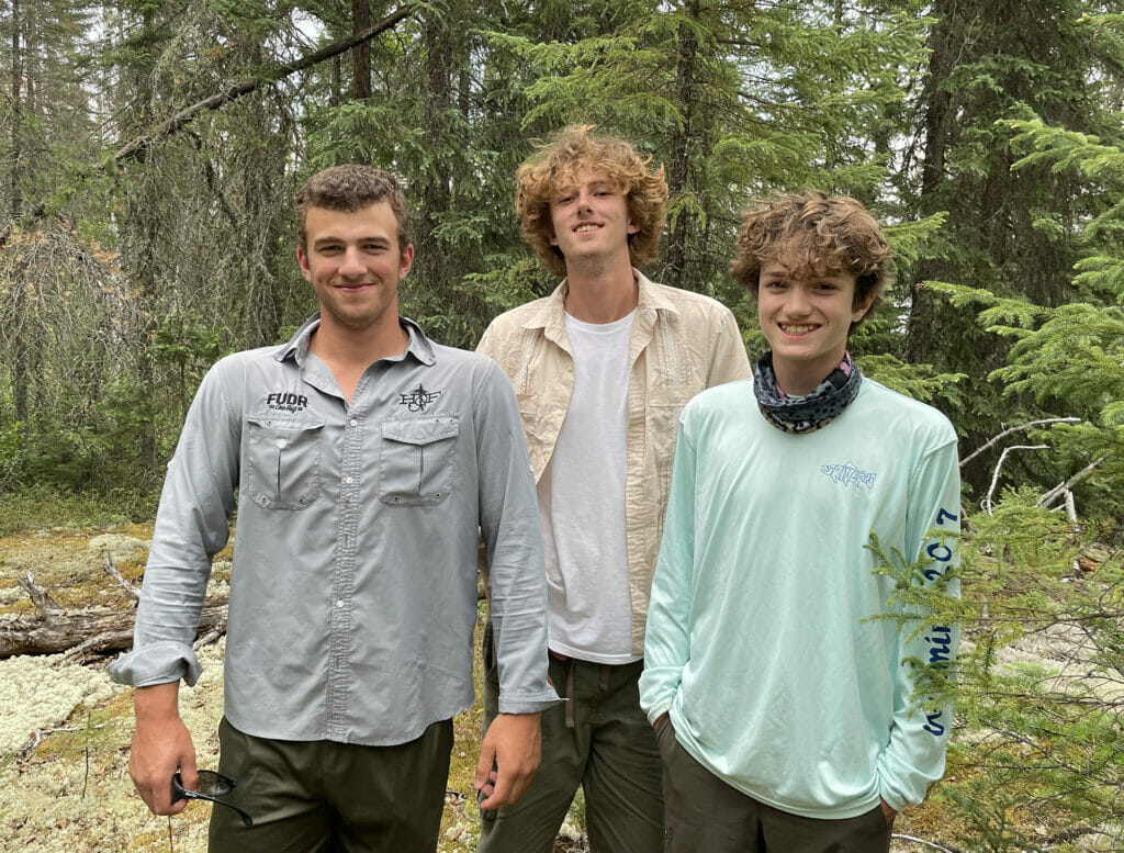 Three young teenage sons smiling proud with the woods behind them teenage sons