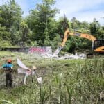 Big machinery tears down a small dam
