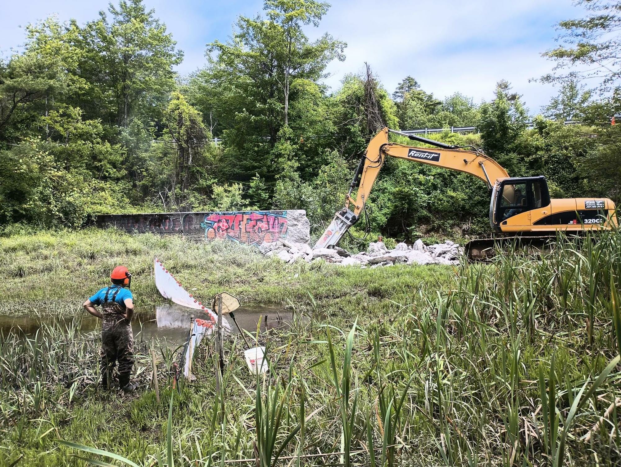 Big machinery tears down a small dam