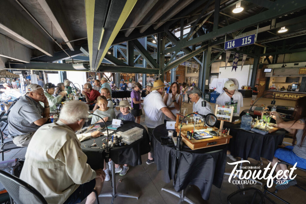 Many tables of people with fly tying equipment