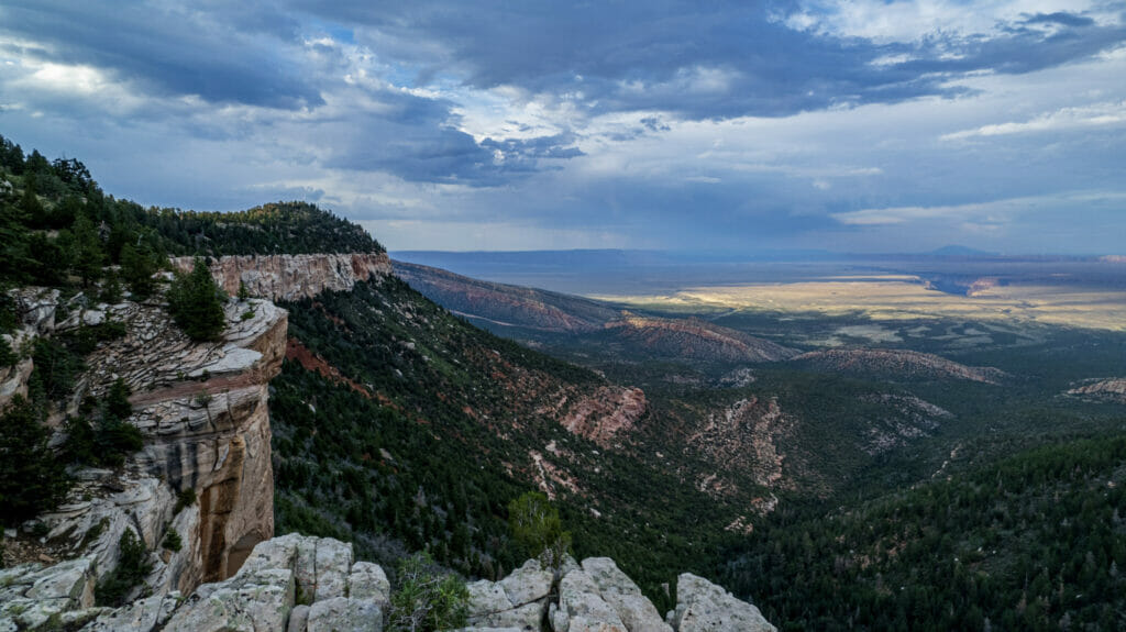 View from the top of the Grand Canyon of a vast plain with rain clouds far away