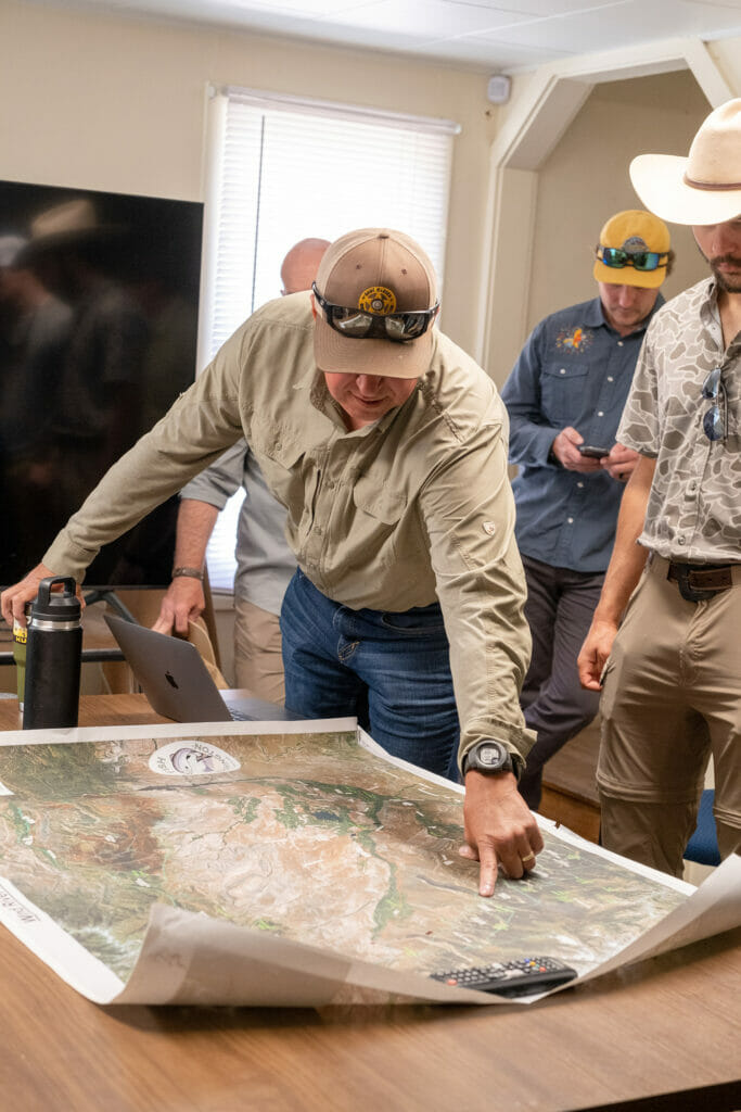 Group of people look at a map of the Wind River Indian Reservation on a table