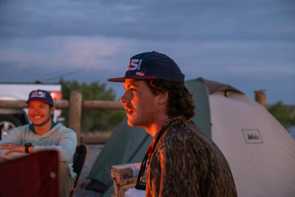 College age students sitting around a campfire at night