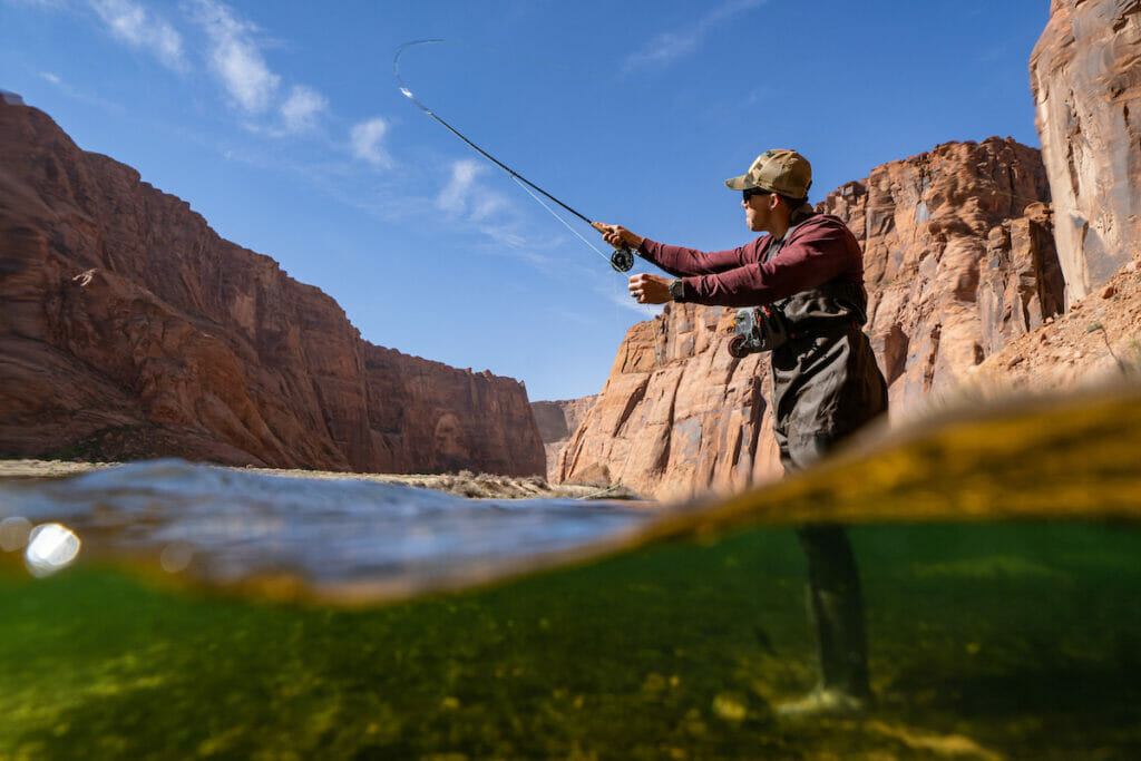 A view from partially below the water line of a man casting a fly rod