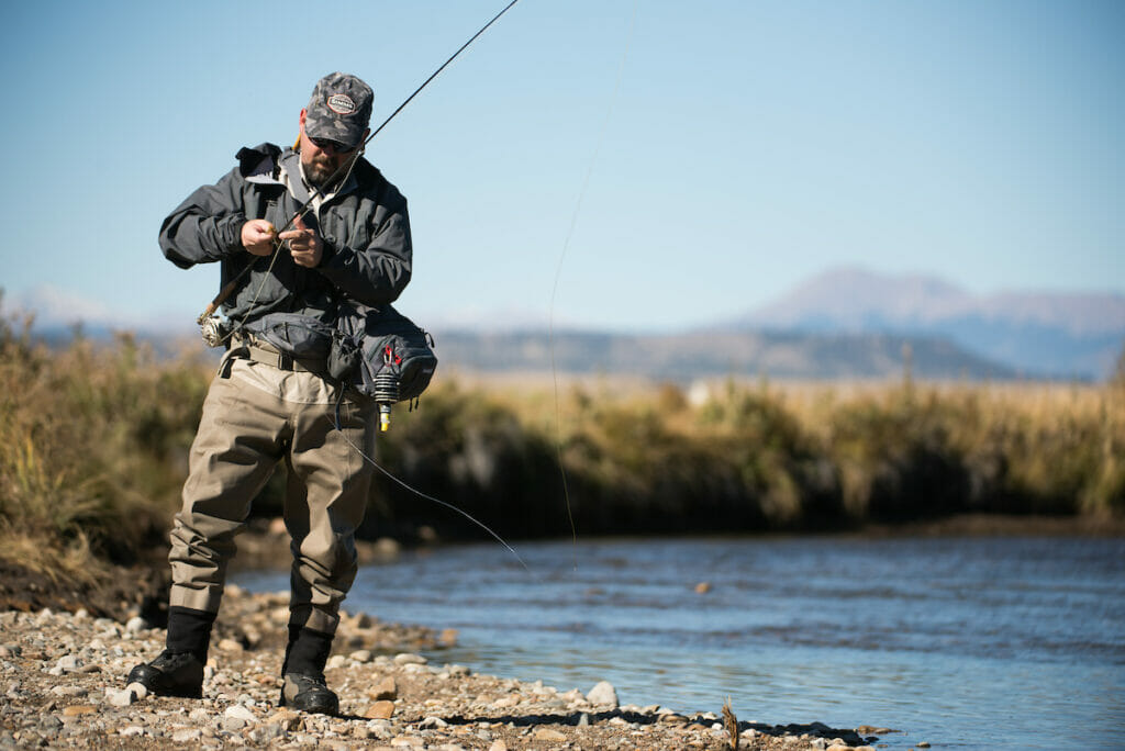 Man adjusting his fishing pole next to some water which is helped by a resource management plan