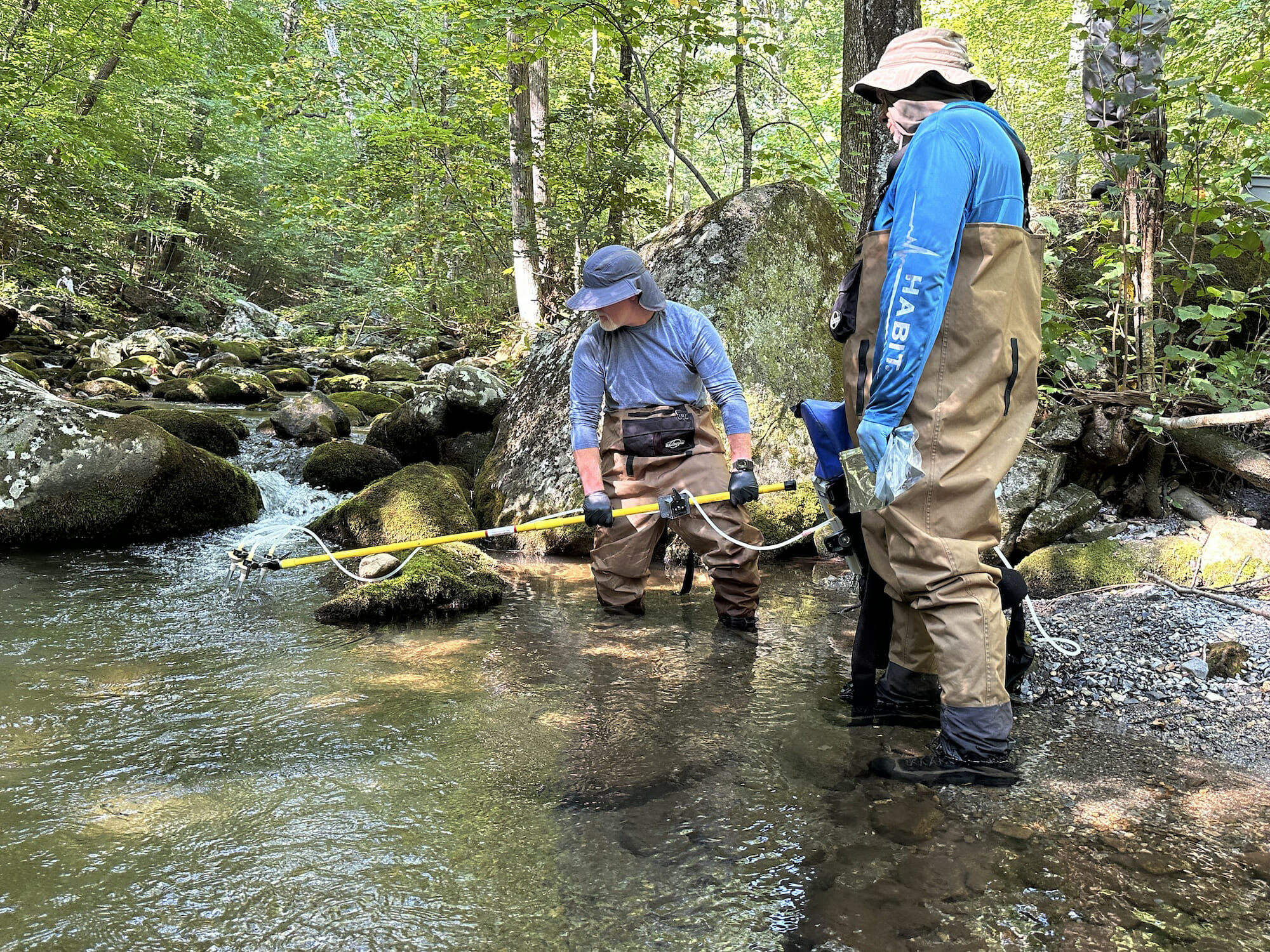 Two men with equipment in a stream