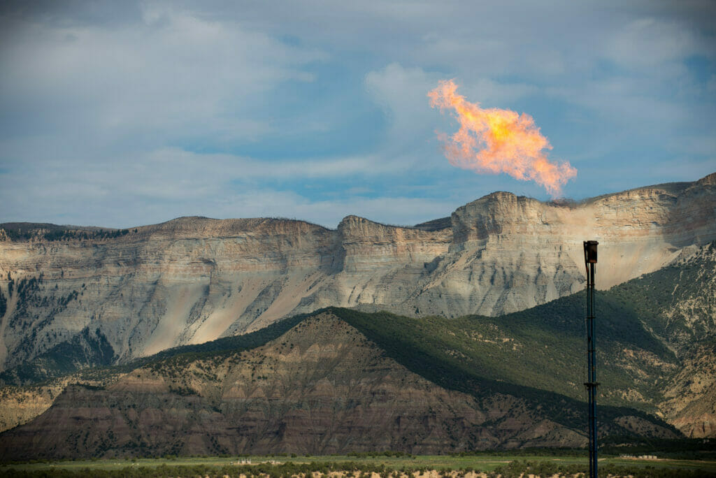 Flames come out of a pipe in front of beautiful mountains