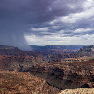 A wide view Multi-colored levels of the Grand Canyon with rain coming in from the left