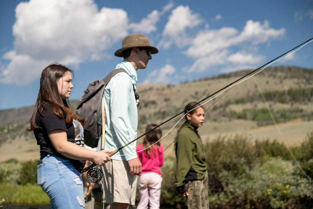 College age students fishing with younger children