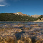 Close up of water in a lake with mountains in the background