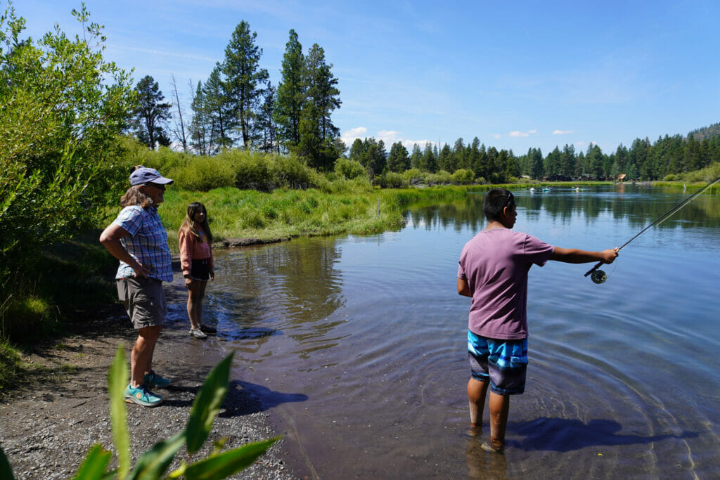 Man fishes while a woman and child watch