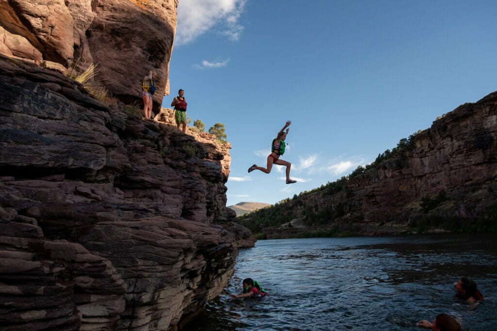 A teen age girl jumping off a cliff into the water