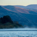 Mist rises off of a river on a beautiful mountain morning