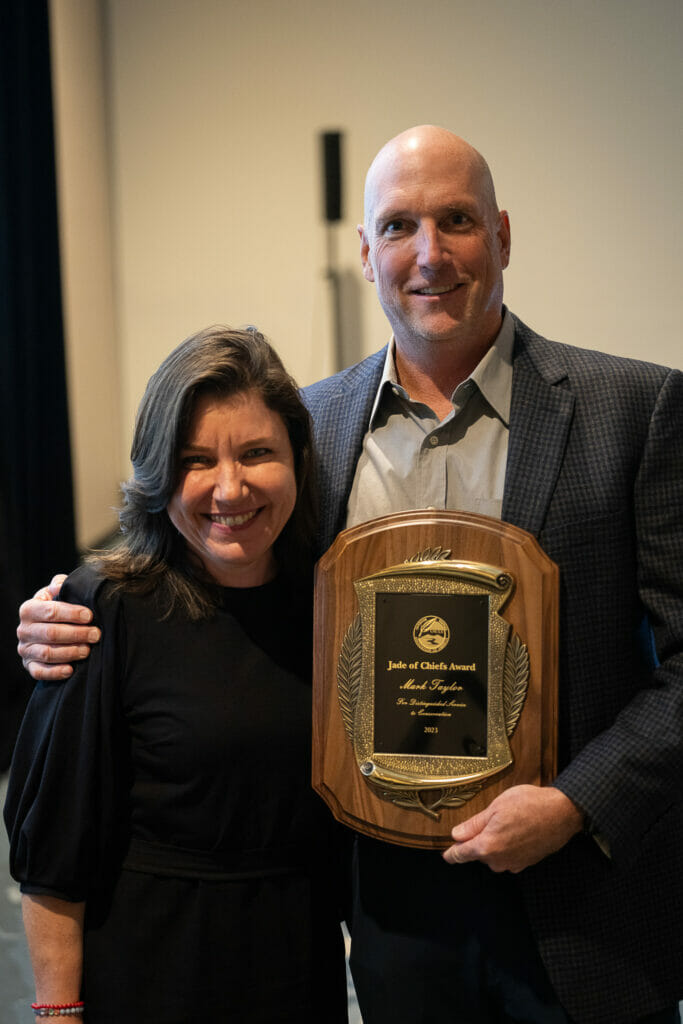 Man holding award has his arm around a woman to his right