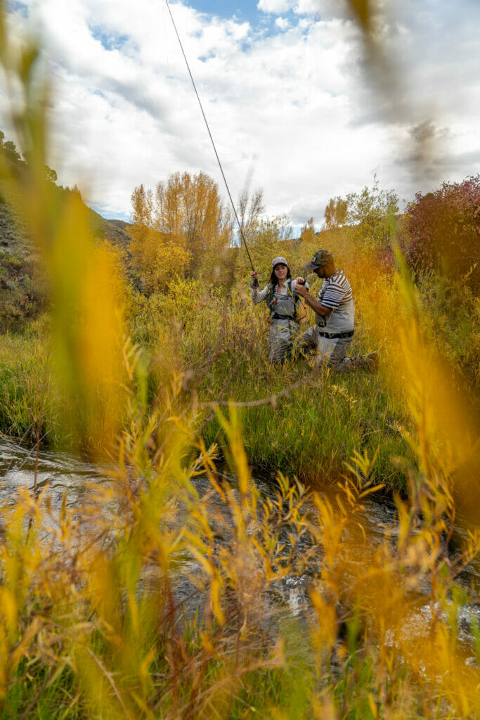 Man and woman fishing with some blurry leaves in the way