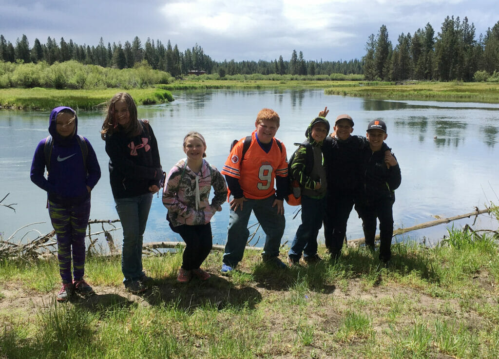 Seven elementary kids pose next to a river