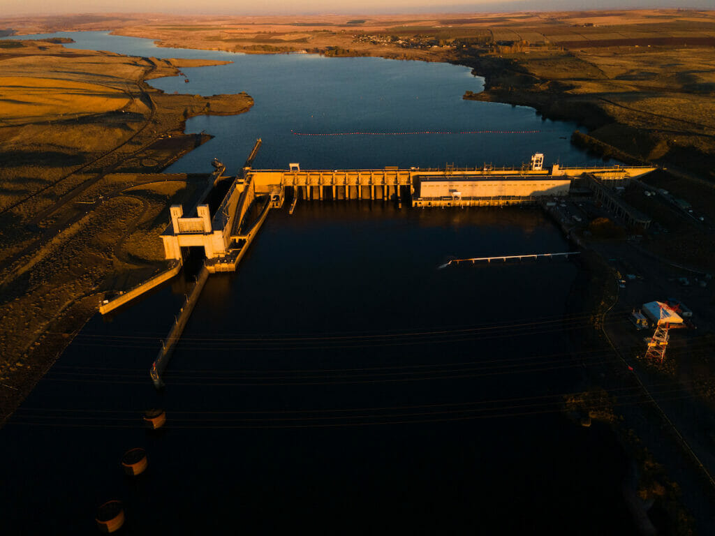 Areal view of a wide damn on a teh Snake River at sunset