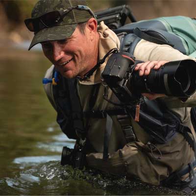 Man with camera wades into water waist deep