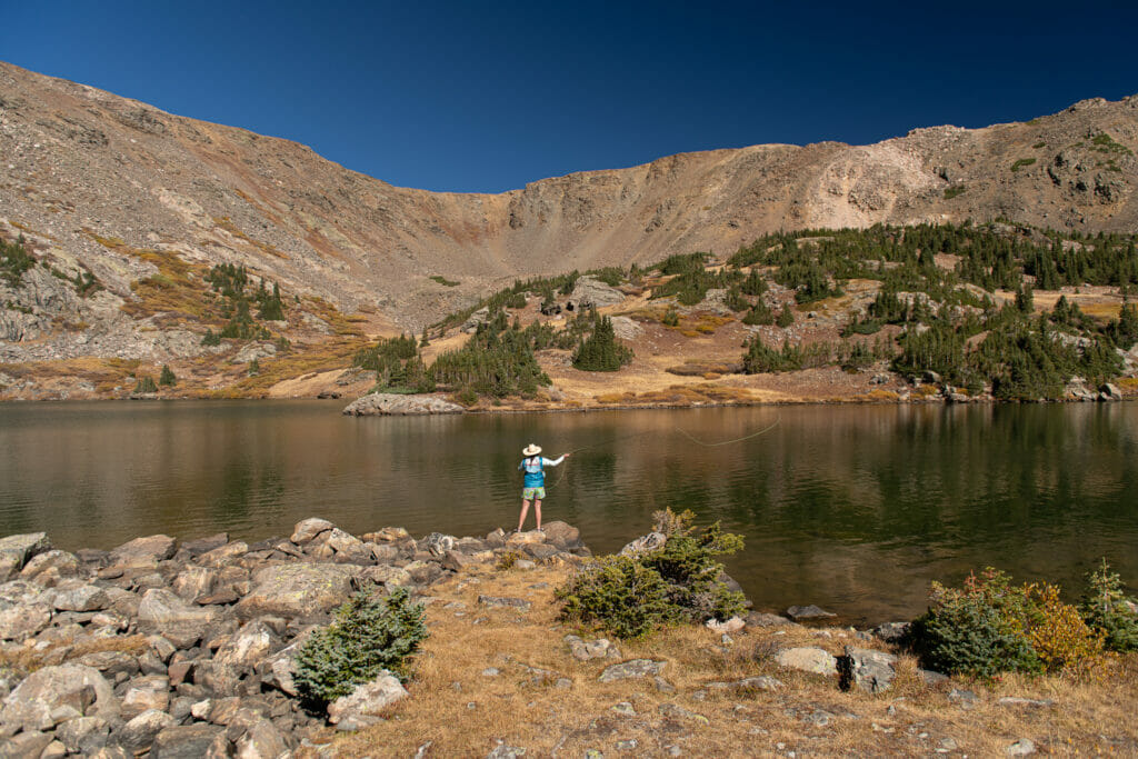 Shot from behind of woman fishing in a ricky lake