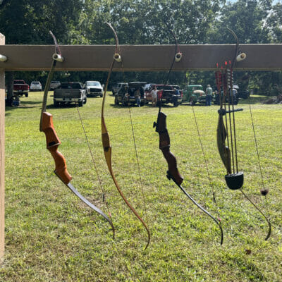 An outdoor rack holding four archery bows