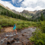 person walking through a stream on public lands roadless area