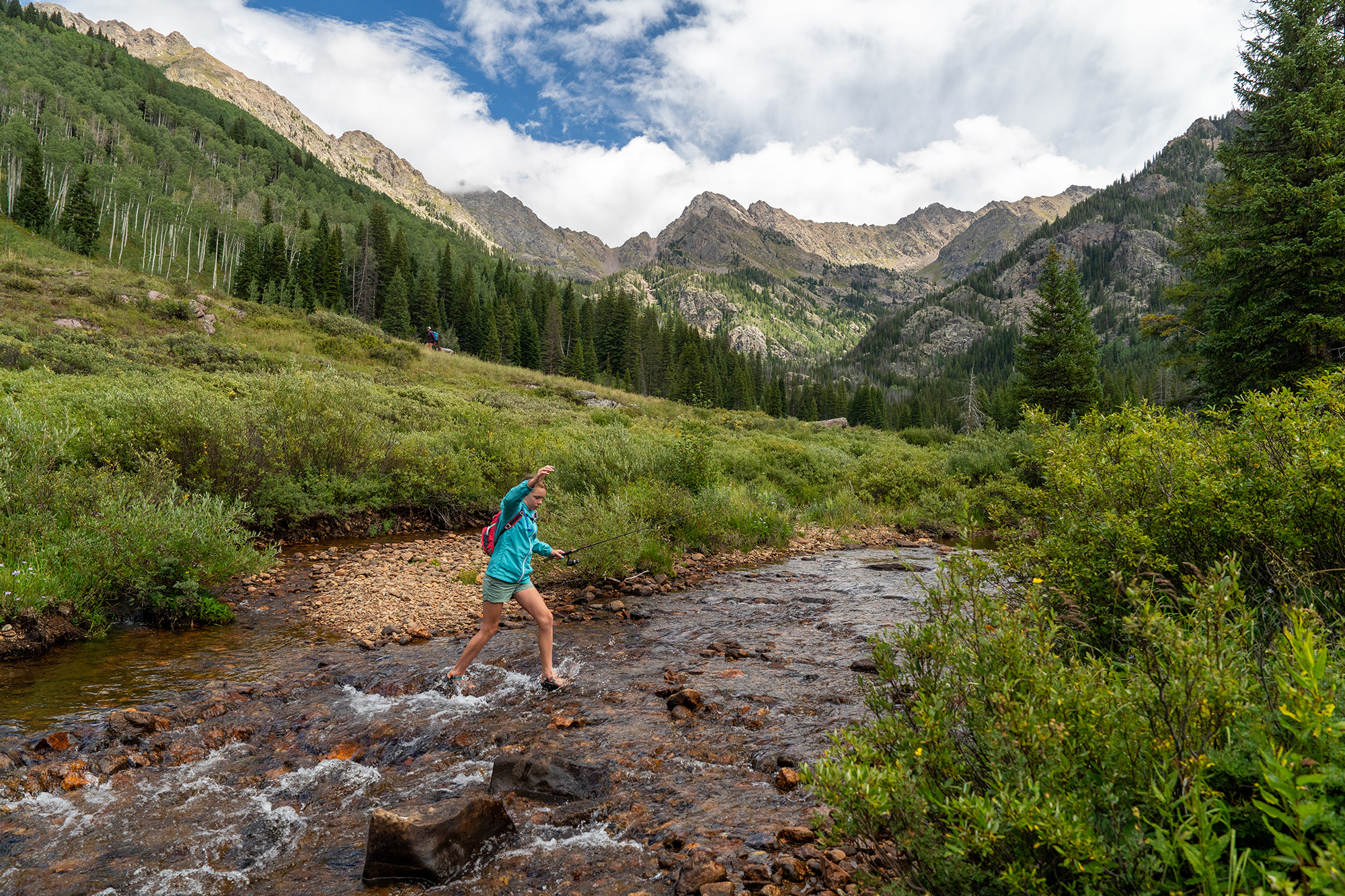 person walking through a stream on public lands roadless area