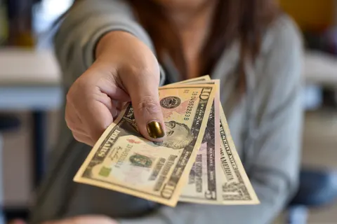 person handing over cash representing the need to know how the reviewer is getting paid