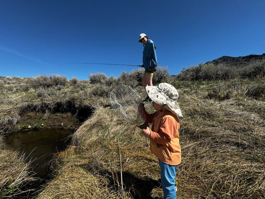 dave sarazin's son holding a net next to a stream