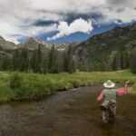 fishing a river mountains in the background with no snow