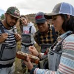 woman holding fly box giving fly fishing tips to small group