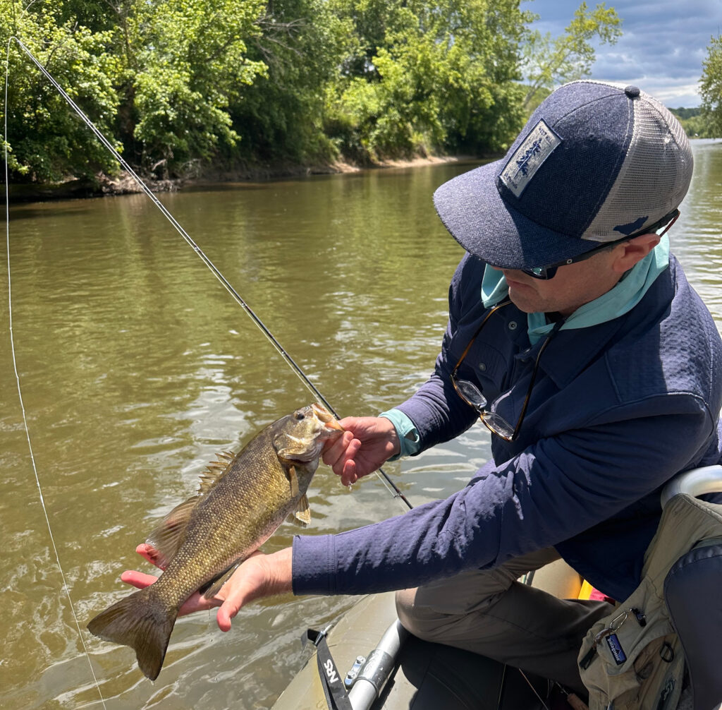 nat g holding a smallmouth caught on a popper