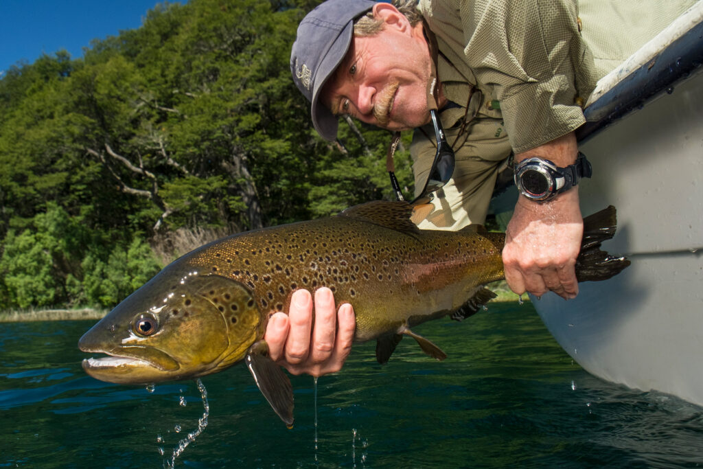 mark lance holding large brown trout out of boat