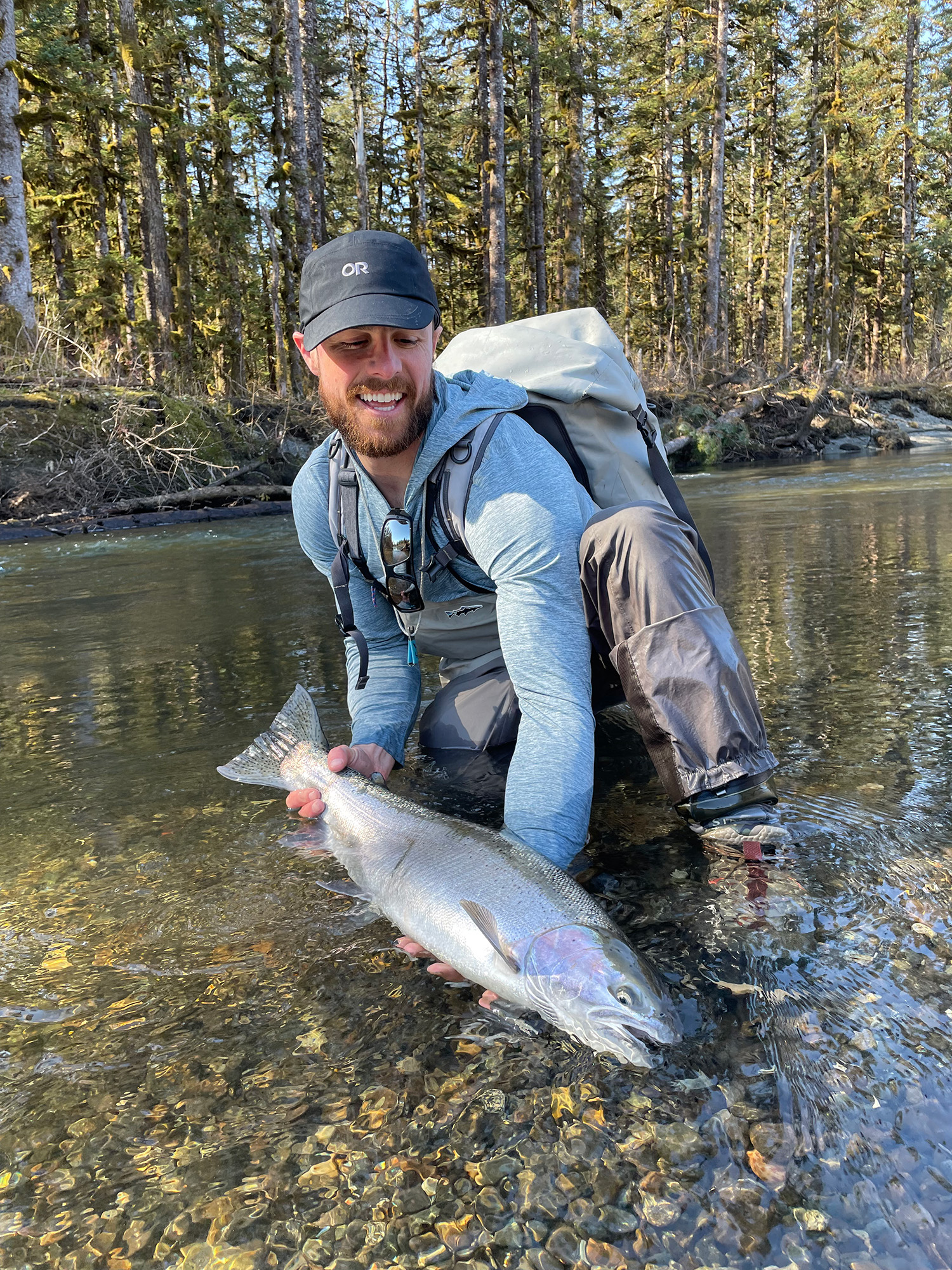 young male angler on situk river with steelhead catch