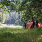 campers in front of tent in forest