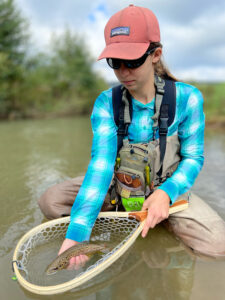 young female angler with brown trout in net